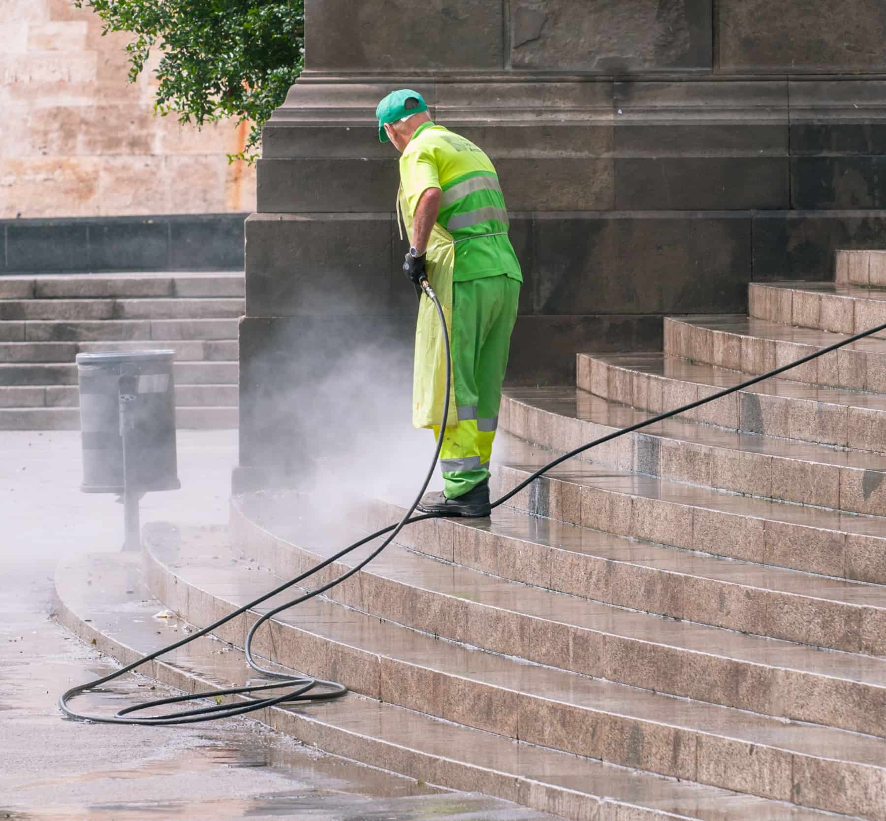 A pressure washer cutting a clean stripe through grimy concrete